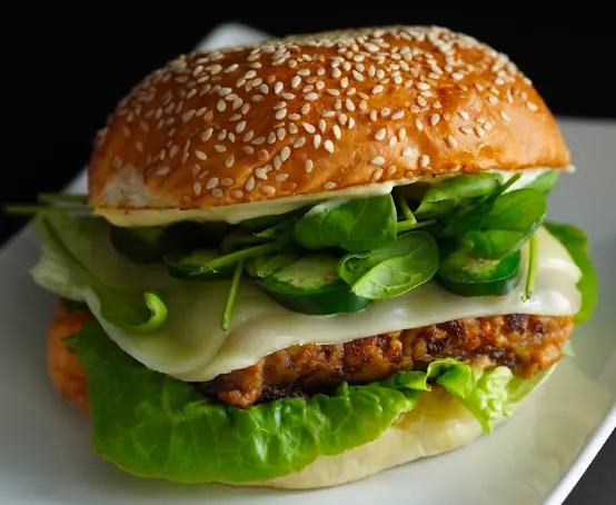 Gourmet burger with sesame bun, cheese, spinach and jalapeños